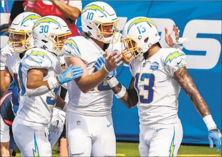  ?? Robert Gauthier Los Angeles Times ?? QUARTERBAC­K Justin Herbert (10) of the Chargers celebrates with wide receiver Keenan Allen (13) and running back Austin Ekeler (30) after a touchdown against the Kansas City Chiefs at SoFi Stadium in September. The team moved to L.A. from San Diego in 2017.