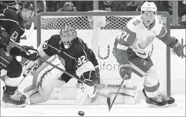  ?? John McCoy Associated Press ?? KINGS DEFENSEMAN Jake Muzzin, left, goalie Jonathan Quick and Red Wings center Dylan Larkin have their eyes on the puck during the second period. The Kings scored three goals in the third period for the win.