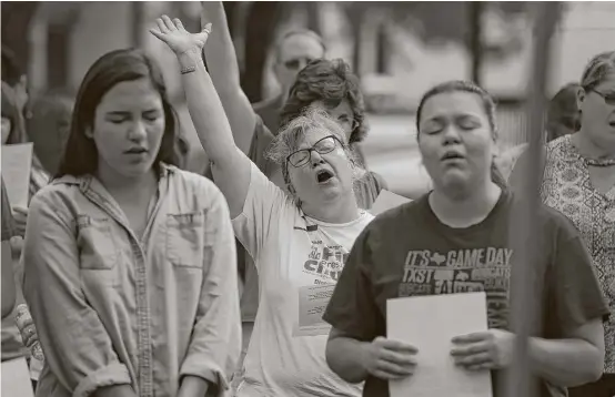  ?? Steve Gonzales photos / Houston Chronicle ?? Marilee Norred gives praise Sunday during a service on the front lawn of the First Presbyteri­an Church of Dickinson, which was badly damaged by flooding.