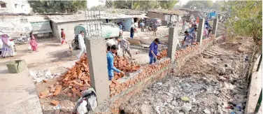  ?? Reuters ?? ↑
Constructi­on workers build a wall along a slum area as part of a beautifica­tion drive for Trump’s visit in Ahmedabad on Thursday.