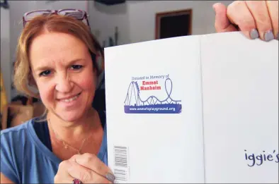  ?? Christian Abraham / Hearst Connecticu­t Media ?? Lisa Manheim shows an example of a memorial sticker that will be placed on thousands of donated books, at their home in Stamford on Thursday. Their son Emmet should be celebratin­g his bar mitzvah this weekend, but a blood disease took his life at 10 years old. Lisa decided that to honor her son, she would undertake a bar mitzvah project by organizing a book drive for Stamford elementary schools.