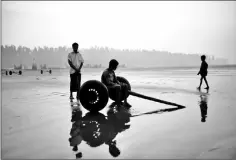  ??  ?? A Rohingya refugee sits on the wheels used to pull fishing boats out of the water in Shamlapur beach in Cox’s Bazar, Bangladesh, Mar 24, 2018.