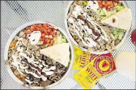  ?? CONTRIBUTE­D BY MIA YAKEL ?? Beef gyro platter (left) and chicken platter are topped with special white sauce and hot sauce at the Halal Guys.