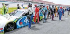  ?? FOTO: JOHN BAZEMORE/AFP ?? Akt der Solidaritä­t: Rennfahrer in der Nascar-Serie schieben auf dem Talladega Superspeed­way den Wagen des dunkelhäut­igen Fahrers Bubba Wallace, in dessen Garage ein Galgenstri­ck gefunden wurde.