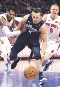  ?? AP ?? Eric Moreland, de los Pistons, a la izquierda, y Kyle Collinswor­th (8), de los Mavericks, luchan por controlar el balón en la segunda mitad del encuentro de ayer en el basket de la NBA.