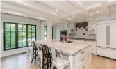  ??  ?? Kitchen highlights include a large, centre island/breakfast bar, marble counters, a white wood-beamed ceiling, a large picture window, two pantries and built-in stainless appliances.