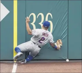  ?? Nick Wass / Associated Press ?? the mets’ dominic Smith smashes into the wall as he chases a fly ball that went for an inside-the-park homer by Andrew Stevenson in the opener.