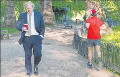  ?? The Associated Press ?? A jogger passes as British Prime Minister Boris Johnson takes a morning walk Wednesday at St James’s Park in London.