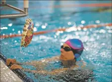  ??  ?? Stephanie Daffron’s mask hangs off the diving block while she swims Wednesday (Sept. 16) at the Taos Youth and Family Center.