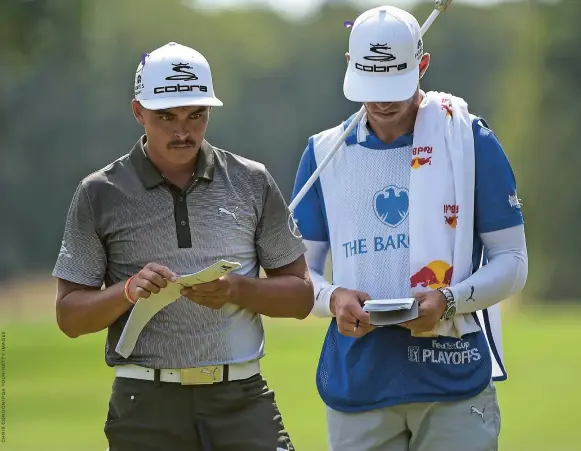  ??  ?? RICKIE FOWLER AND CADDIE STUDY THEIR GREEN MAPS DURING THE FEDEX CUP PLAYOFFS .