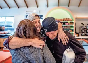  ?? RYAN GARZA/DETROIT FREE PRESS ?? Donut Villa owner Gabriel Gutierrez hugs Debra Ryder, left, of Detroit and her husband, Kevin, right, while talking with the couple after they stopped in to purchase paczki on Feb. 13 at the shop that is in southwest Detroit and recently reopened following renovation­s.