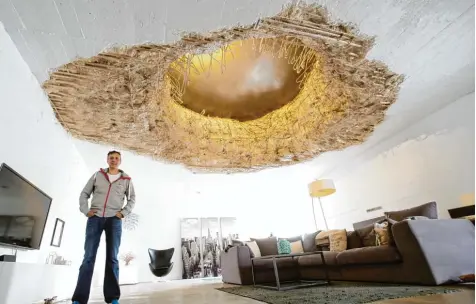  ?? Fotos: Roland Weihrauch, dpa ?? Architekt Martin Heimeier steht im Wohnzimmer eines Mieters. Er hat einen ehemaligen Weltkriegs Hochbunker zu einem Wohnhaus umgebaut. Das Loch in der Decke ist kein Kunstwerk, sondern zeugt von einem Bombentref­fer.