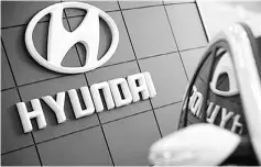  ??  ?? The Hyundai logo is seen next to the company’s Sonata sedan at a dealership in Seoul. South Korean automakers face a major headwind from a weakening Japanese yen, which will boost rivals like Toyota Motor next year, a Hyundai Motor think tank said. —...