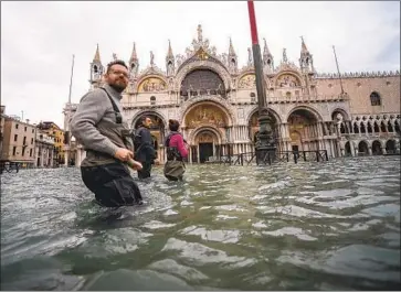  ?? FILIPPO MONTEFORTE AFP/Getty Images ?? PEOPLE WADE through f looded St. Mark’s Square, which police cordoned off Friday, in Venice, Italy. More than 50 churches have been damaged, and experts were deployed to assess the city’s artworks.