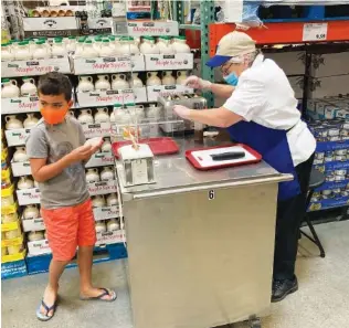  ?? AP PHOTO/DAVID ZALUBOWSKI ?? A worker offers a sample of a waffle flavored with a featured maple syrup at a Costco warehouse in June in Lone Tree, Colo. With vaccinatio­ns rolling out and the threat of COVID-19 easing in the U.S., stores are feeling confident enough to revive the longstandi­ng tradition of offering free samples. For customers, sampling makes it fun to shop and discover new items, not to mention getting all the freebies.