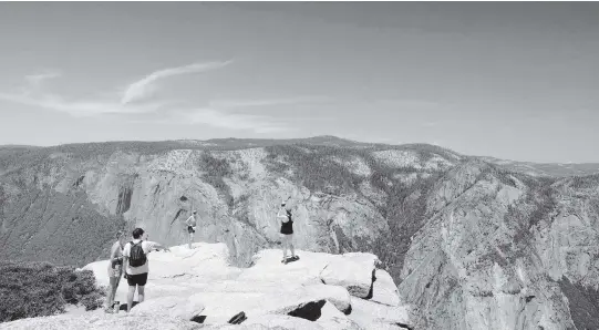  ?? PHOTOS BY MARK HUME Chicago Tribune/TNS ?? Hikers brave a ledge thousands of feet above the Yosemite Valley floor to snap photos in Yosemite National Park. The view is along the Sentinel Dome and Taft Point 5-mile loop trail. Photograph made with a polarizing filter on the lens. (Mark Hume/Chicago Tribune/TNS)