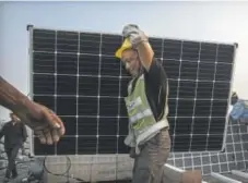  ?? Kevin Frayer, Getty Images ?? A Chinese worker carries a solar panel in Huainan, Anhui Province, China. A proposed U.S. tariff on solar imports could double the price of panels.