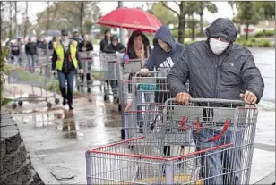  ?? Mel Melcon Los Angeles Times ?? DURING THE EARLY days of the pandemic in March, shoppers waited — some masked, some not — in a line that wrapped around the block to enter a Costco in Woodland Hills.