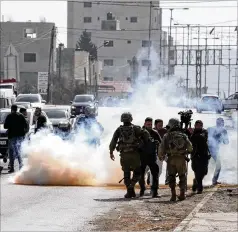  ?? MAYA ALLERUZZO/ASSOCIATED PRESS ?? Palestinia­n journalist­s run from tear gas fired by Israeli soldiers Friday toward Palestinia­ns after they attacked Israeli cars in the West Bank town of Hawara.