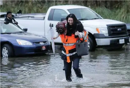  ?? Elizabeth Conley / Houston Chronicle ?? A woman gets a lift from a Houston firefighte­r after leaving her car on a flooded Texas 288 on Wednesday. The most recent flooding in Houston comes just weeks before the Super Bowl.