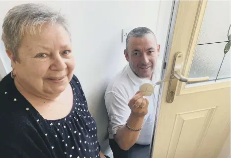  ?? ?? Dot Brown (71) from the Aged Miners Cottages watching on as Cllr Phil Tye fits the door handle alarm.