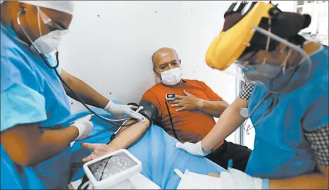  ?? REBECCA BLACKWELL/AP ?? Dr. Anahi Moreno, right, and Giovanni Barragan attend to a patient in a mobile health clinic Wednesday in Mexico City.