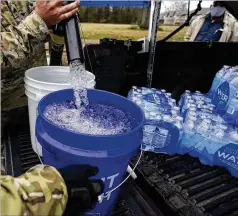  ?? ROGELIO V. SOLIS/ AP ?? Members of the Mississipp­i Army National Guard fill five-gallon buckets with non-potable water at a Jackson, Miss., distributi­on site weeks after winter storms wreaked havoc on the city’s water system.