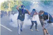  ?? AP PHOTO/EVAN VUCCI ?? Demonstrat­ors who had gathered Monday to protest the death of George Floyd begin to run from tear gas used by police to clear the street near the White House in Washington.