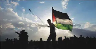  ??  ?? AGITATION: A Palestinia­n protester uses a slingshot to hurl stones at Israeli troops during clashes on the Gaza-Israel border, east of Gaza City, on Friday.