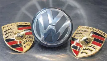  ?? FOTO: DPA ?? Zwei Porsche-Logos mit einem Logo von Volkswagen: Rund neun Jahre nach dem gescheiter­ten Übernahmev­ersuch von VW durch Porsche soll ein milliarden­schwerer Prozess den Anlegern Klarheit bringen.