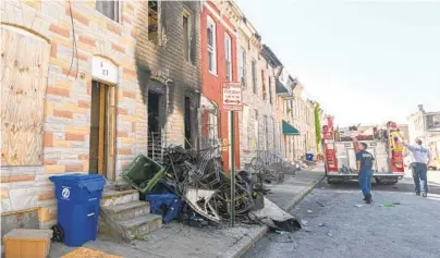  ?? JERRY JACKSON/BALTIMORE SUN ?? Firefighte­rs walk past the charred front of a vacant rowhouse on Furrow Street in the Carrollton Ridge neighborho­od in West Baltimore.