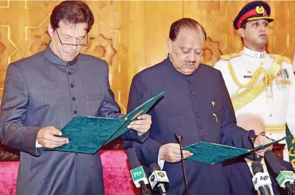  ??  ?? Pakistan’s new Prime Minister, Imran Khan, left, takes the oath of office with the country’s president, Mamnoon Hussain.