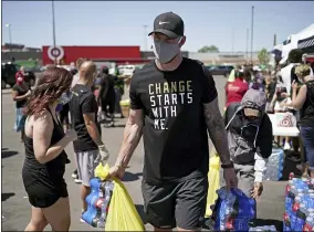  ?? BRIAN PETERSON — STAR TRIBUNE VIA ASSOCIATED PRESS ?? Minnesota Vikings NFL football player Kyle Rudolph helps a woman carry items to her car at the “Change Starts with Me” food and household supply giveaway outside a Cub Foods store in Minneapoli­s on June 5.