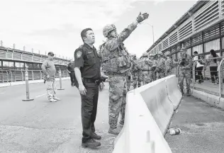  ??  ?? Army and Customs and Border Protection personnel prepare to install protective wire at the internatio­nal bridge in Hidalgo. At one point, Trump suggested the GIs would be allowed to shoot anyone who threw rocks at them, but he later walked back that comment.