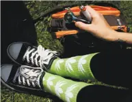  ?? Sarah Rice / Special to The Chronicle 2014 ?? Above, Jessica Morales wears socks decorated with marijuana leaves as she celebrates 4/20 at Hippie Hill in 2014. Left, revelers watch a skywriter overhead at last year’s unofficial event in Golden Gate Park. This year, the city is officially...