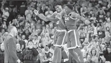  ?? Jayne Kamin-Oncea Getty Images ?? AARON HOLIDAY, right, and Chris Smith aren’t celebratin­g like this over the Bruins’ selection to a play-in game, but they’re glad to be there. “We’re going out to play and win a championsh­ip,” Holiday says.