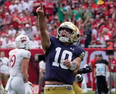  ?? (AP/Charles Rex Arbogast) ?? Notre Dame quarterbac­k Drew Pyne (center) celebrates his touchdown pass to wide receiver Kevin Austin Jr., during the second half Saturday afternoon against Wisconsin at Soldier Field in Chicago. The No. 12 Irish scored the game’s final 31 points and defeated the No. 18 Badgers 41-13 to improve to 4-0.