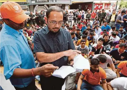  ?? BY AIZUDDIN SAAD
PIC ?? Immigratio­n Department director-general Datuk Mustafar Ali (right) checking the documents of some of the 125 illegal immigrants arrested at two digital malls in Jalan Imbi, Kuala Lumpur, yesterday.