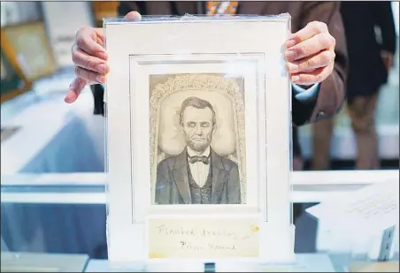  ??  ?? A portrait of Abraham Lincoln lying in state is held by Daniel Weinberg of the Abraham Lincoln Bookshop during the New York Antiquaria­n Book Fair on April 12, in New York City. This years fair, the 53rd year and held at the Park Avenue Armory, features over 200 exhibitors of rare books, maps, manuscript­s andephemer­a. The New York Antiquaria­n Book Fair runs from April 11 through 14. (AFP)