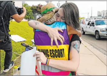  ?? Rogelio V. Solis The Associated Press ?? Derenda Hancock, co-director of the Jackson Women’s Health Organizati­on clinic patient escorts, better known as the Pink House defenders, left, hugs abortion rights supporter Sonnie Bane, outside the clinic in Jackson, Miss., on Wednesday.