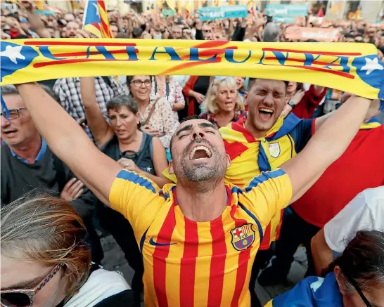  ?? REUTERS ?? A man waves a scarf with a Catalan flag design as he joins the crowd in Barcelona’s Sant Jaume Square to hear the Catalan regional parliament declare independen­ce from Spain.