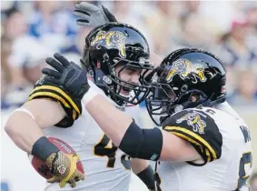  ?? JOHN WOODS/THE Canadian Press ?? Hamilton Tiger-Cats’ John Delahunt, left, and Greg Wojt celebrate Delahunt’s touchdown
against the Winnipeg Blue Bombers in Hamilton’s 37-18 win in Winnipeg on Friday.