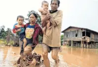  ?? PHOTO: REUTERS ?? Escaping . . . Parents carry their children as they leave their home during the flood after the XepianXe Nam Noy hydroelect­ricity dam collapsed in Laos.