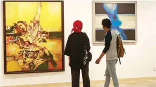  ?? ?? Visitors look at paintings by Iraqi artists Suad Al-Attar (left) and Rafa Al-Nasri (right) on display at Iraq’s Ministry of Culture in Baghdad.