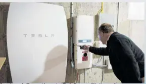  ??  ?? A customer in Vermont inspects a Tesla Powerwall battery unit.