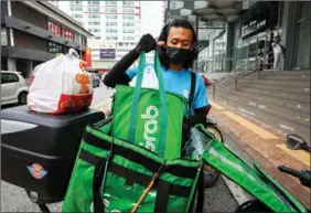  ?? AFP ?? A Grab delivery rider places a package inside a thermal bag to keep food warm for a customer in Kuala Lumpur, Malaysia.