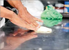  ?? HENG CHIVOAN ?? Mohammed Rashid, who was resettled in Cambodia from a detention centre on Nauru island, prepares the dough for roti at his food cart.