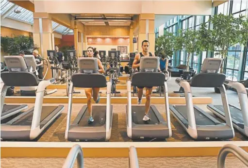  ?? . RJ Sangosti, The Denver Post ?? Brian and Monica Folts work out on treadmills at Colorado Athletic Club Tabor Center on May 16