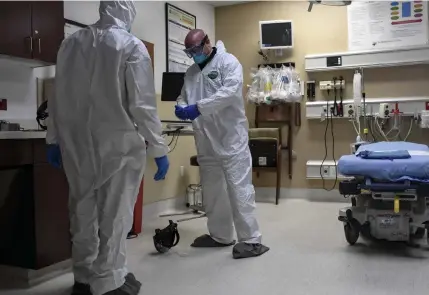  ?? Aaron Ontiveroz, The Denver Post ?? Aurora firefighte­rs Mike Manaoat, left, and Brandon Sauder remove their protective clothing on April 22 after taking a patient via stretcher to the emergency room at the Medical Center of Aurora.