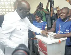  ?? ABBAS DULLEH/THE ASSOCIATED PRESS ?? Former soccer star and presidenti­al candidate George Weah, left, casts his vote during a presidenti­al runoff election in Monrovia, Liberia, on Tuesday.